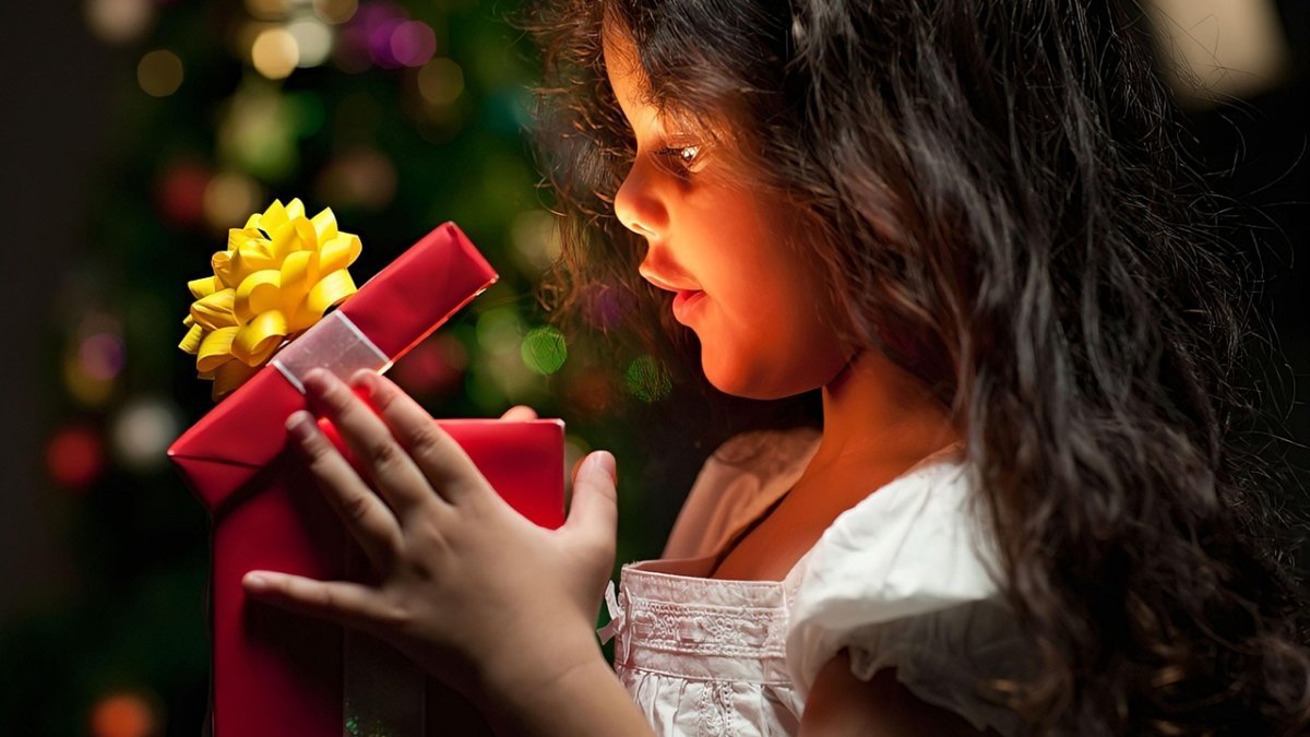 Child opening a Christmas present, very happy at what's glowing in the box.